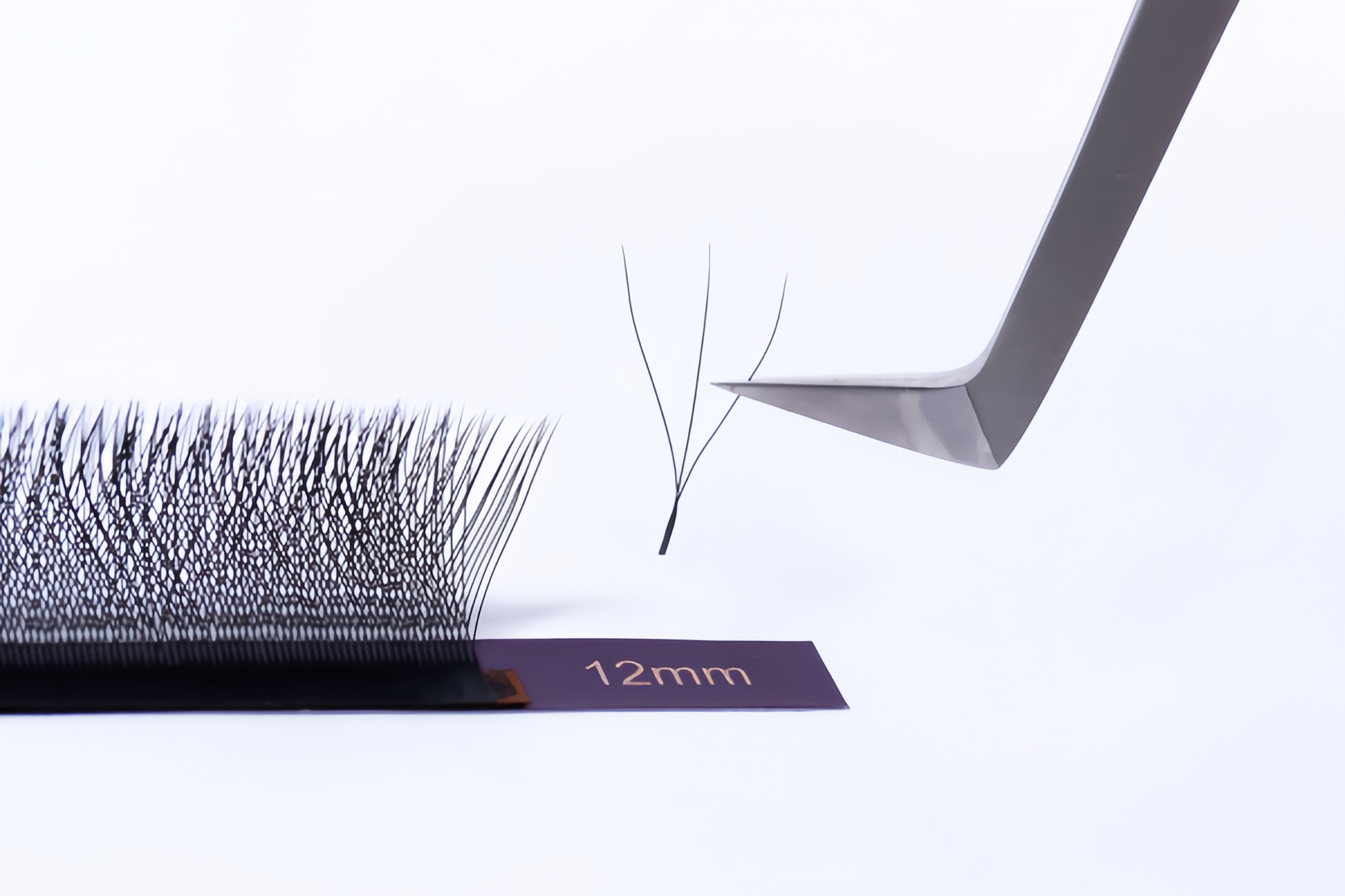W 3D pre made volume lash fan picked up with tweezers showing precise W shape